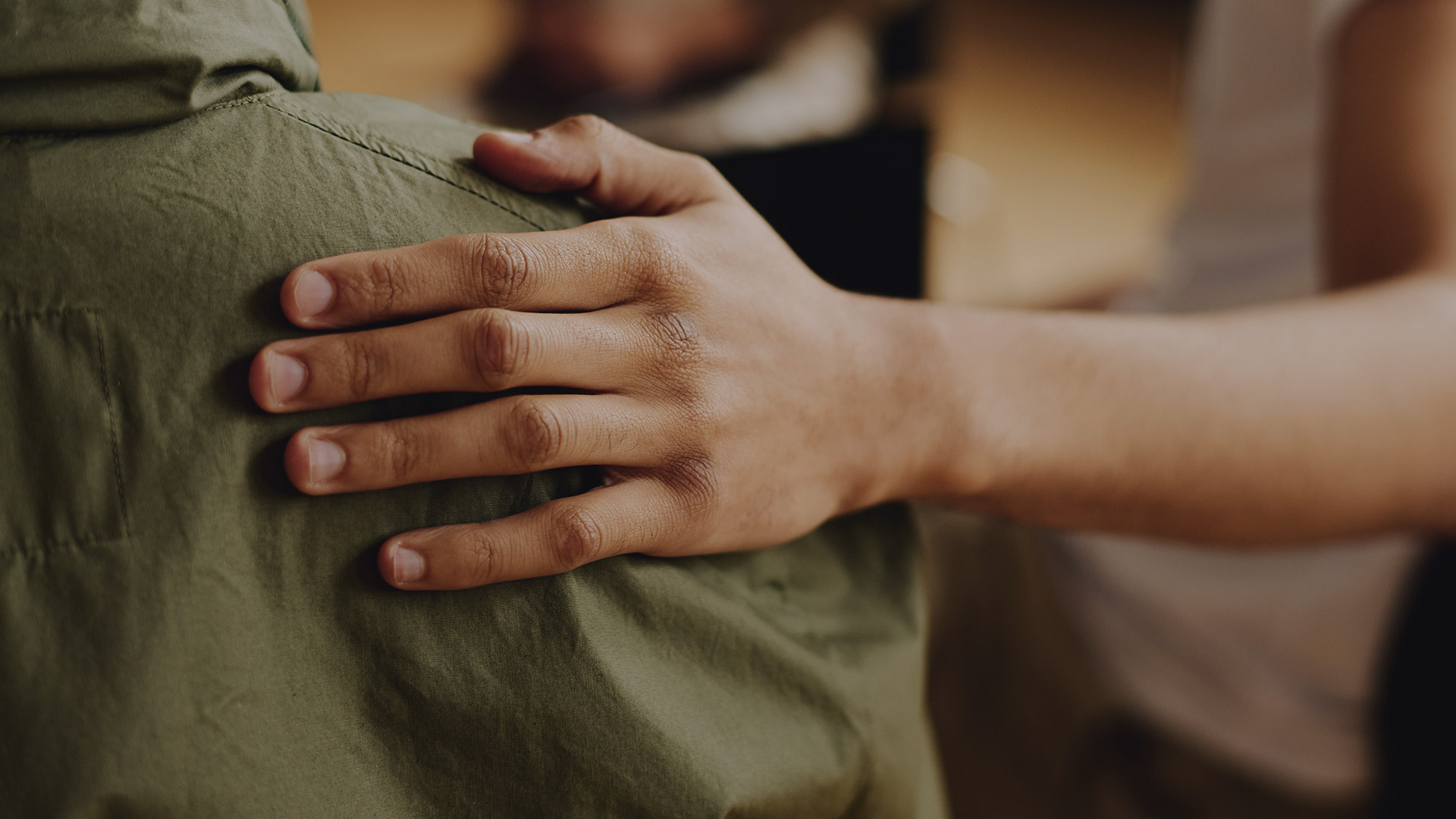A person's hand giving a supportive touch on another individual's back. PEP supports families dealing with addiction in loved ones.