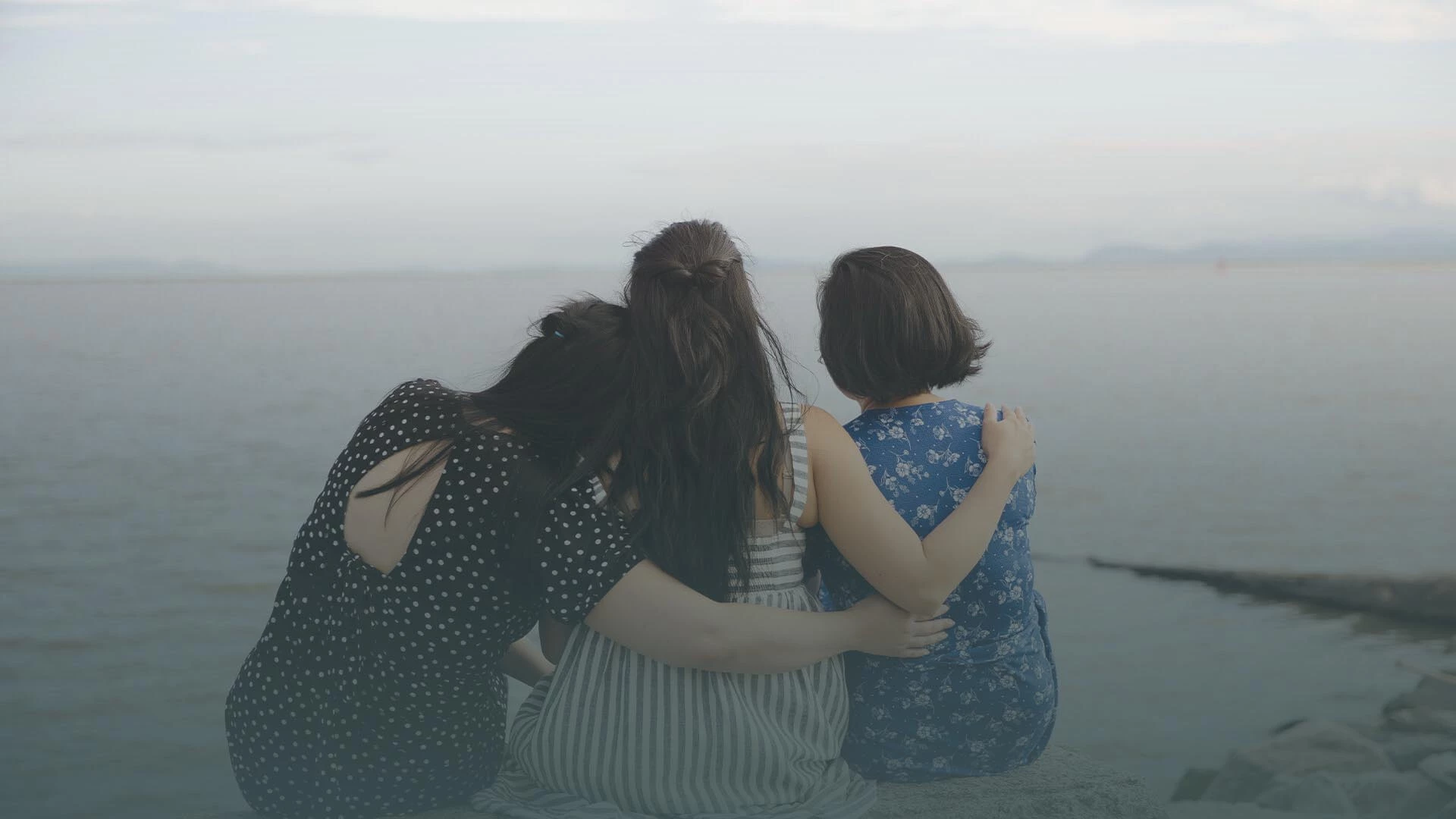 girls hugging while looking at the ocean